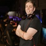 Smiling gamer with headphones in esports arena, exuding confidence and modern vibe.